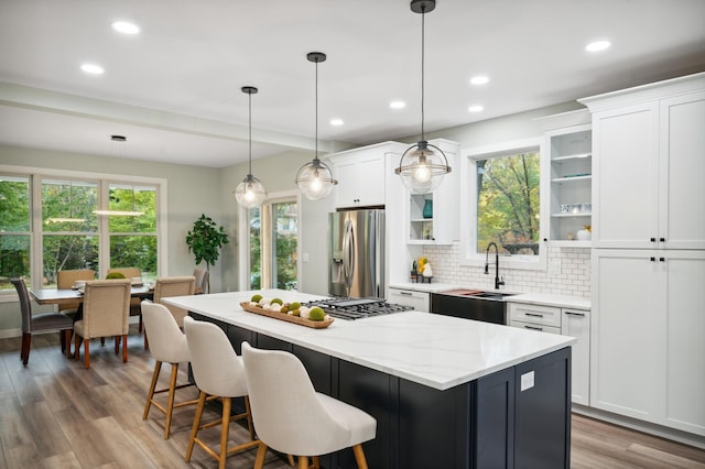 kitchen featuring a kitchen island, appliances with stainless steel finishes, pendant lighting, and white cabinets