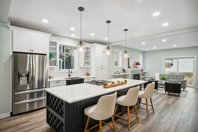 kitchen featuring a kitchen island, pendant lighting, sink, white cabinets, and stainless steel appliances