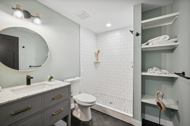 bathroom with vanity, a tile shower, tile patterned floors, and toilet