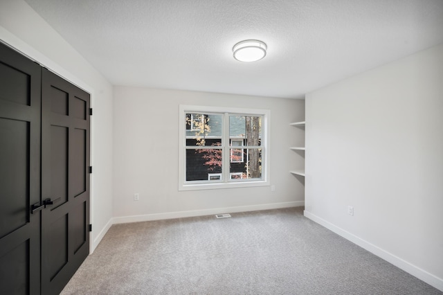 spare room featuring carpet flooring and a textured ceiling