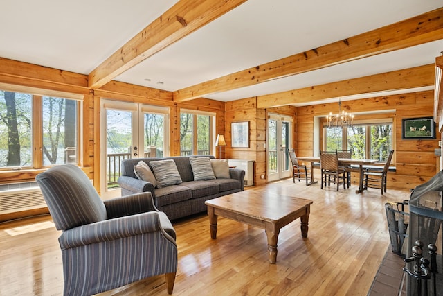 living room featuring light hardwood / wood-style flooring, wooden walls, a notable chandelier, french doors, and beamed ceiling