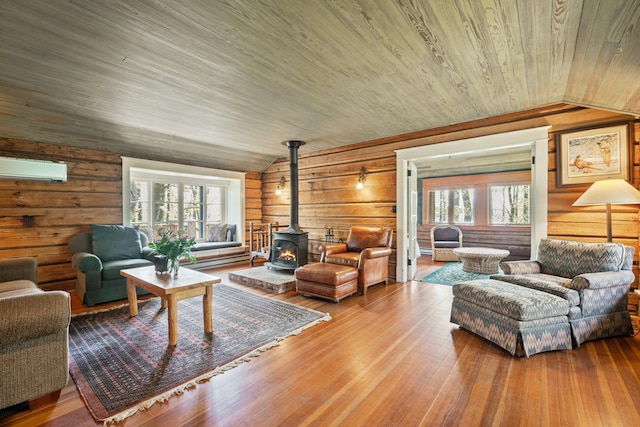 living room with a wealth of natural light, a wood stove, hardwood / wood-style floors, and a wall unit AC