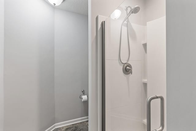 bathroom with a textured ceiling and a shower with door