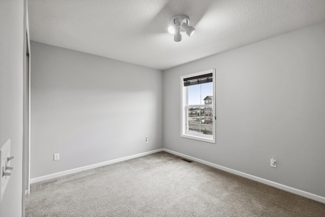 carpeted spare room featuring a textured ceiling