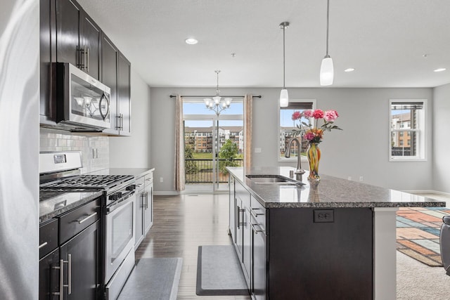 kitchen featuring backsplash, light wood-type flooring, appliances with stainless steel finishes, sink, and pendant lighting
