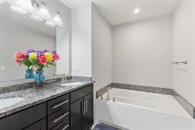 bathroom featuring a bath and dual bowl vanity
