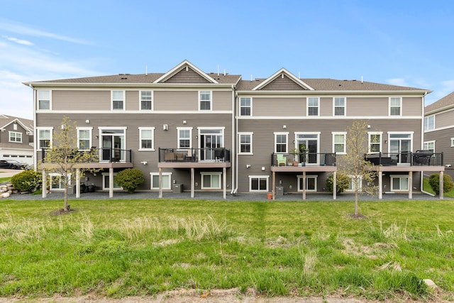 rear view of property with a balcony and a yard