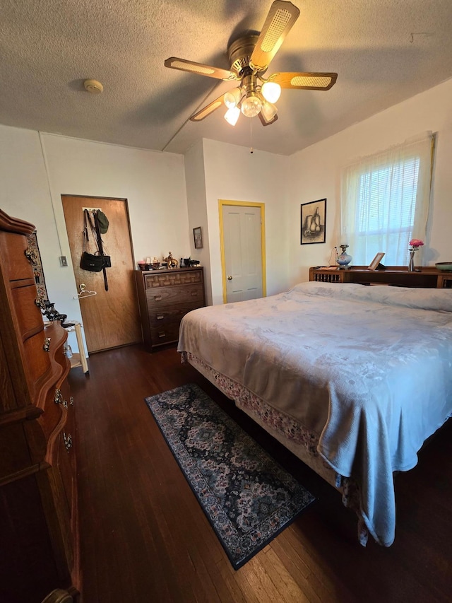 bedroom featuring dark hardwood / wood-style flooring, ceiling fan, and a textured ceiling