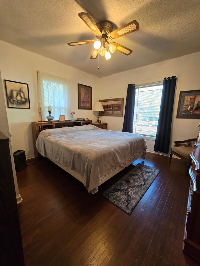 bedroom featuring dark hardwood / wood-style flooring, ceiling fan, and a textured ceiling