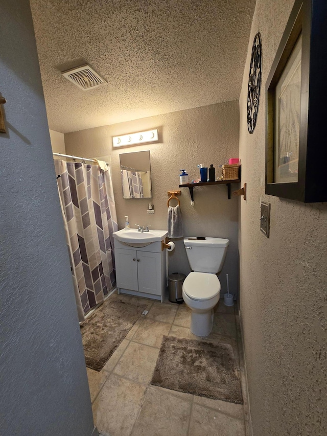 bathroom with toilet, tile floors, vanity, and a textured ceiling