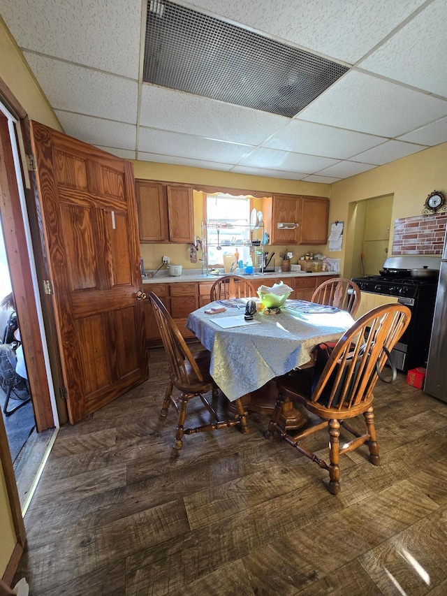 dining area with dark hardwood / wood-style floors and a paneled ceiling