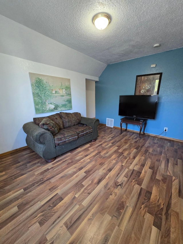 living room with a textured ceiling, dark wood-type flooring, and lofted ceiling