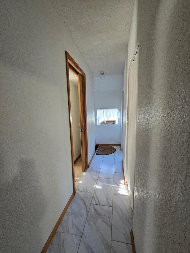 hall with a textured ceiling and light tile flooring