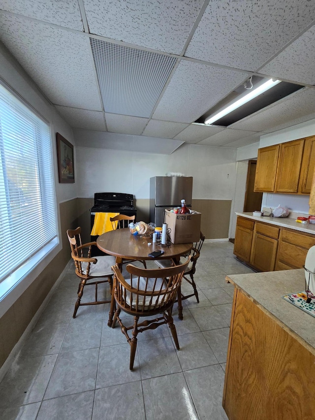 tiled dining area featuring a drop ceiling and plenty of natural light