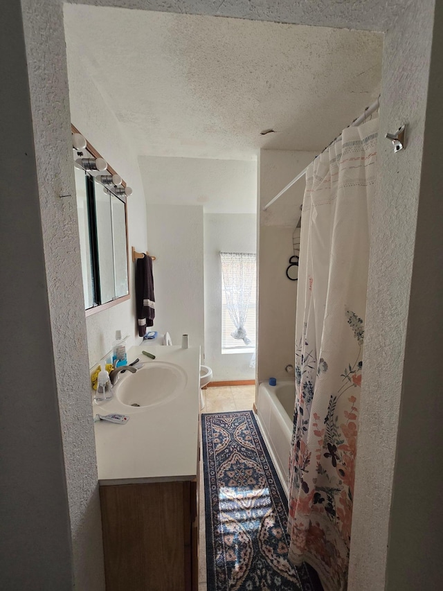 bathroom with tile flooring, a textured ceiling, vanity, and shower / bath combination with curtain