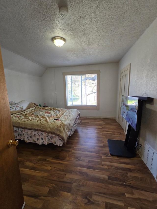 bedroom featuring vaulted ceiling, dark hardwood / wood-style flooring, and a textured ceiling