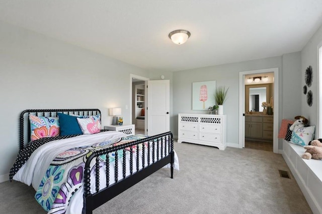 bedroom with ensuite bathroom and light colored carpet