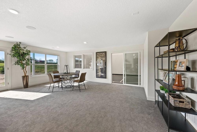 carpeted dining space with a textured ceiling