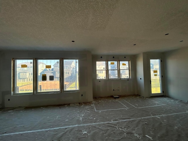 unfurnished room with a textured ceiling and plenty of natural light