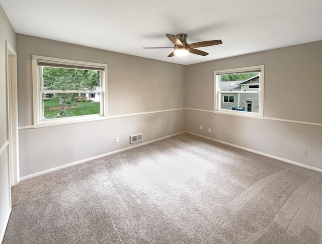 carpeted spare room with a ceiling fan, visible vents, and baseboards