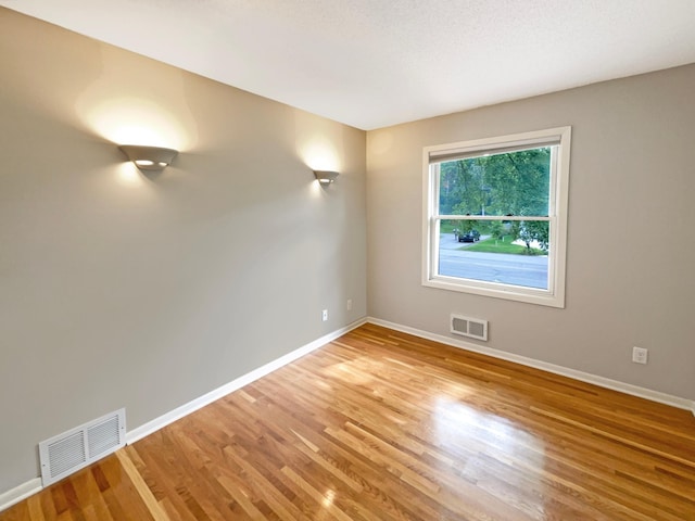 unfurnished room featuring baseboards, visible vents, and light wood finished floors