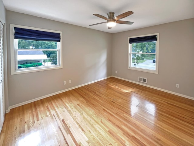 spare room featuring ceiling fan, light wood finished floors, visible vents, and baseboards