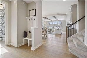 foyer featuring beam ceiling and light wood-type flooring