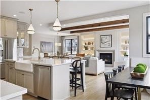 kitchen with a kitchen island with sink, pendant lighting, light hardwood / wood-style floors, and dishwasher