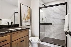 bathroom with a shower with door, vanity, and toilet