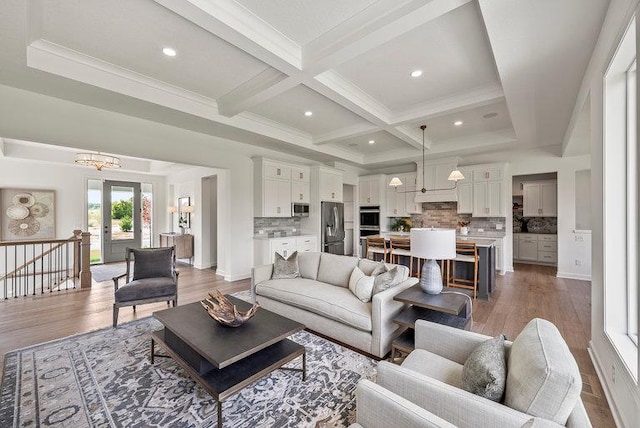 living room featuring wood-type flooring, french doors, beam ceiling, a notable chandelier, and coffered ceiling