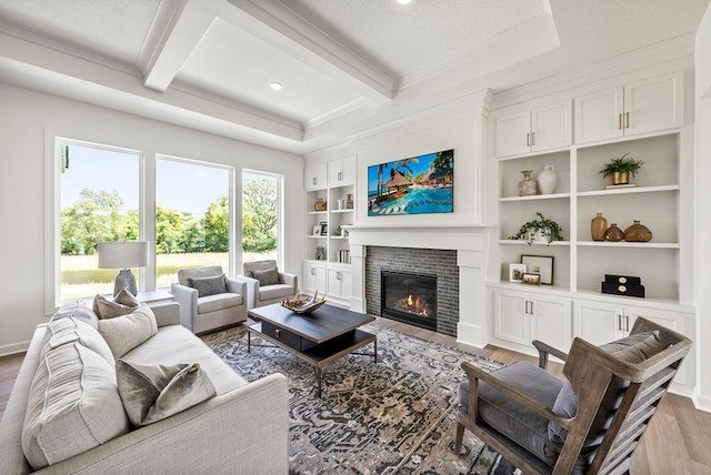 living room with beamed ceiling, light hardwood / wood-style floors, and a textured ceiling