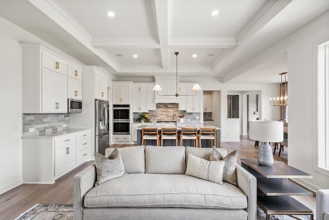 living room featuring beam ceiling, dark hardwood / wood-style flooring, coffered ceiling, and a notable chandelier