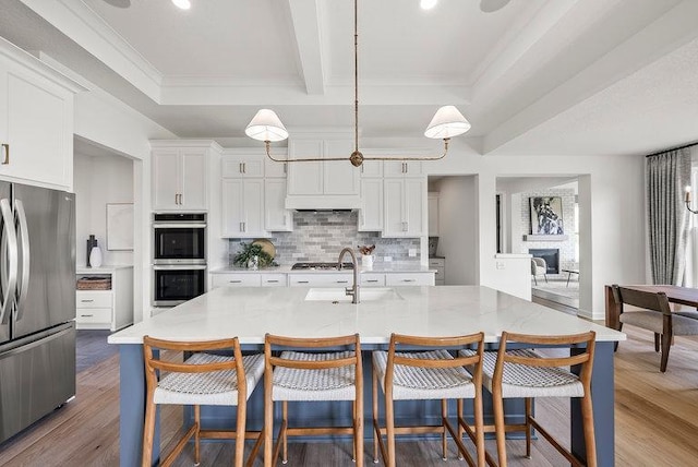 kitchen with appliances with stainless steel finishes, sink, dark wood-type flooring, and backsplash