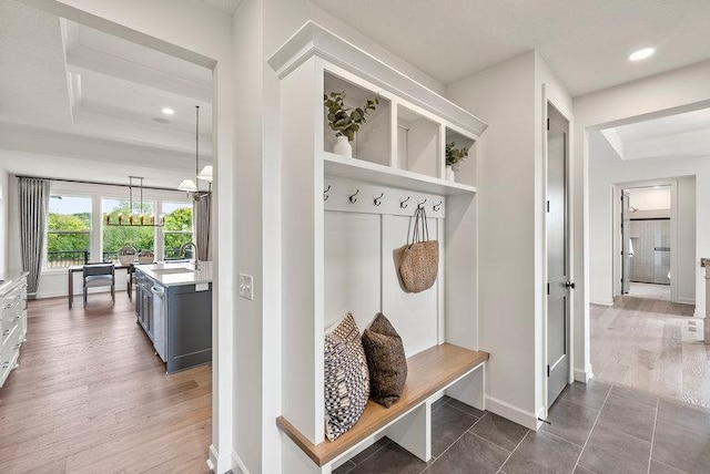 mudroom with dark hardwood / wood-style flooring, sink, a tray ceiling, and an inviting chandelier