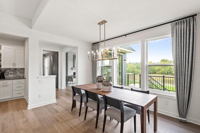 dining space with light hardwood / wood-style floors and an inviting chandelier