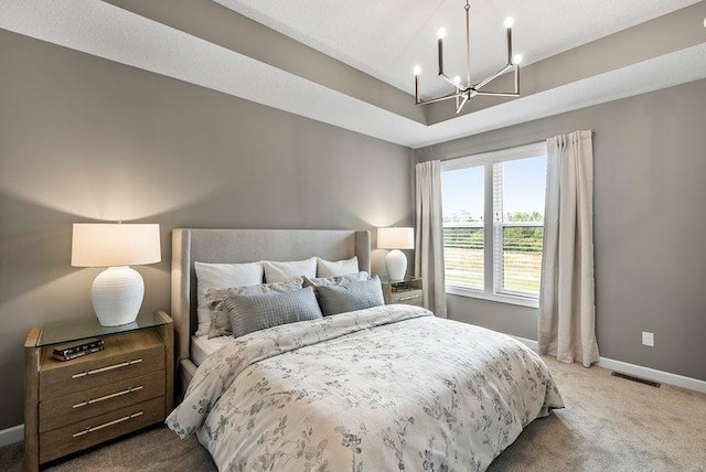 bedroom featuring a notable chandelier, carpet floors, and a tray ceiling