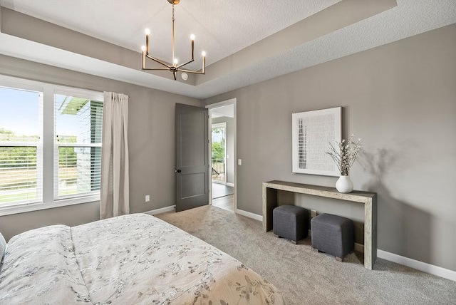 bedroom with a textured ceiling, carpet floors, a raised ceiling, and a chandelier