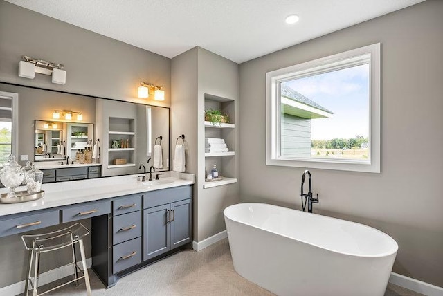 bathroom with a tub, vanity with extensive cabinet space, and built in features