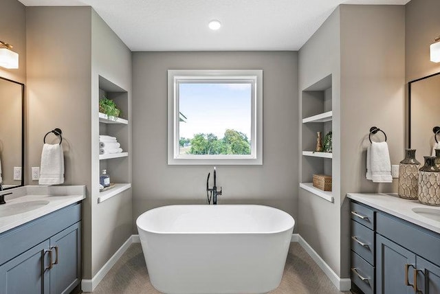 bathroom featuring built in features, dual sinks, oversized vanity, and a bath to relax in