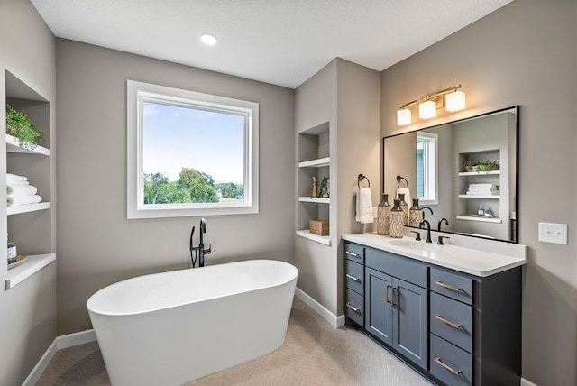 bathroom featuring built in shelves, a bathing tub, vanity, and a textured ceiling