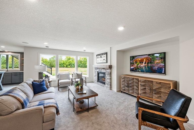 carpeted living room with a textured ceiling, sink, and a stone fireplace