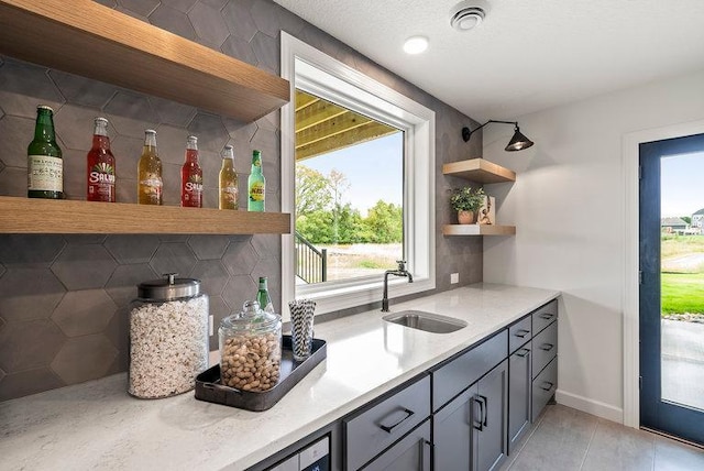 kitchen with a wealth of natural light, tasteful backsplash, gray cabinets, and sink