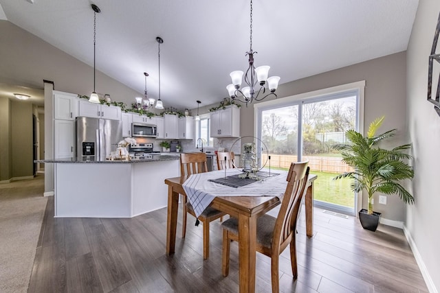 dining area featuring a notable chandelier, wood-type flooring, high vaulted ceiling, and sink