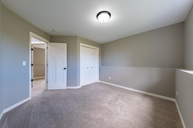 unfurnished bedroom with a textured ceiling, carpet, and a closet