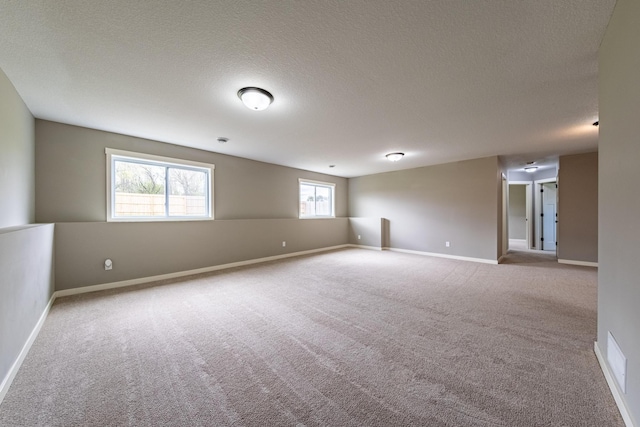 carpeted empty room with a textured ceiling and a wealth of natural light