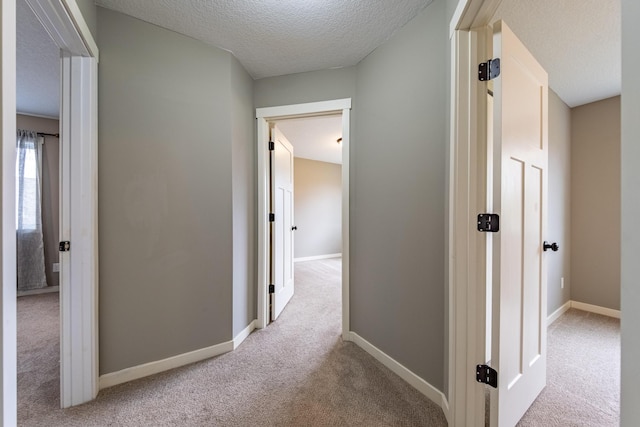 hall featuring light carpet and a textured ceiling