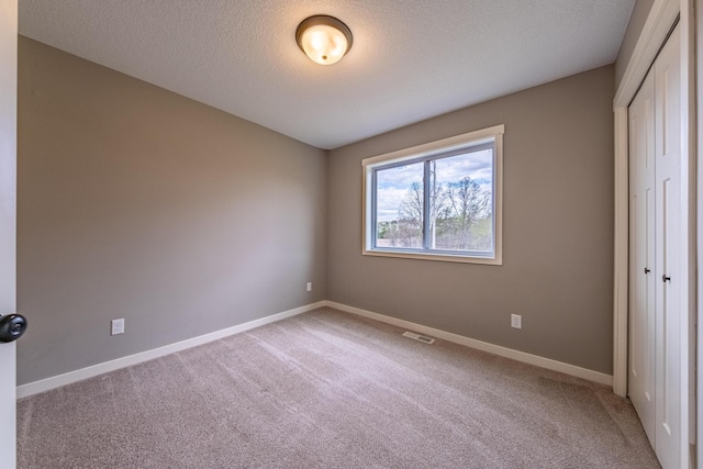 unfurnished bedroom with a closet, a textured ceiling, and carpet flooring