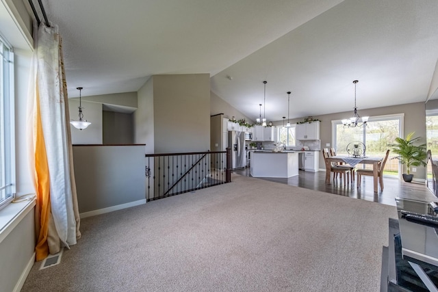 carpeted living room featuring lofted ceiling and an inviting chandelier