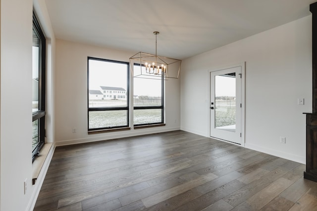 unfurnished dining area featuring a notable chandelier and dark hardwood / wood-style flooring