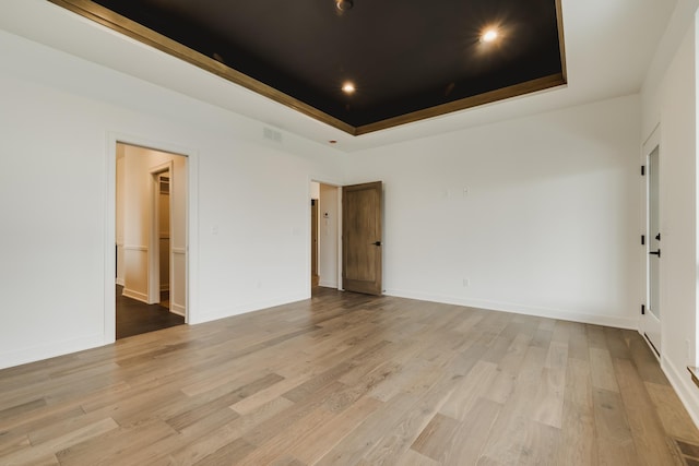 unfurnished room featuring light wood-type flooring and a tray ceiling